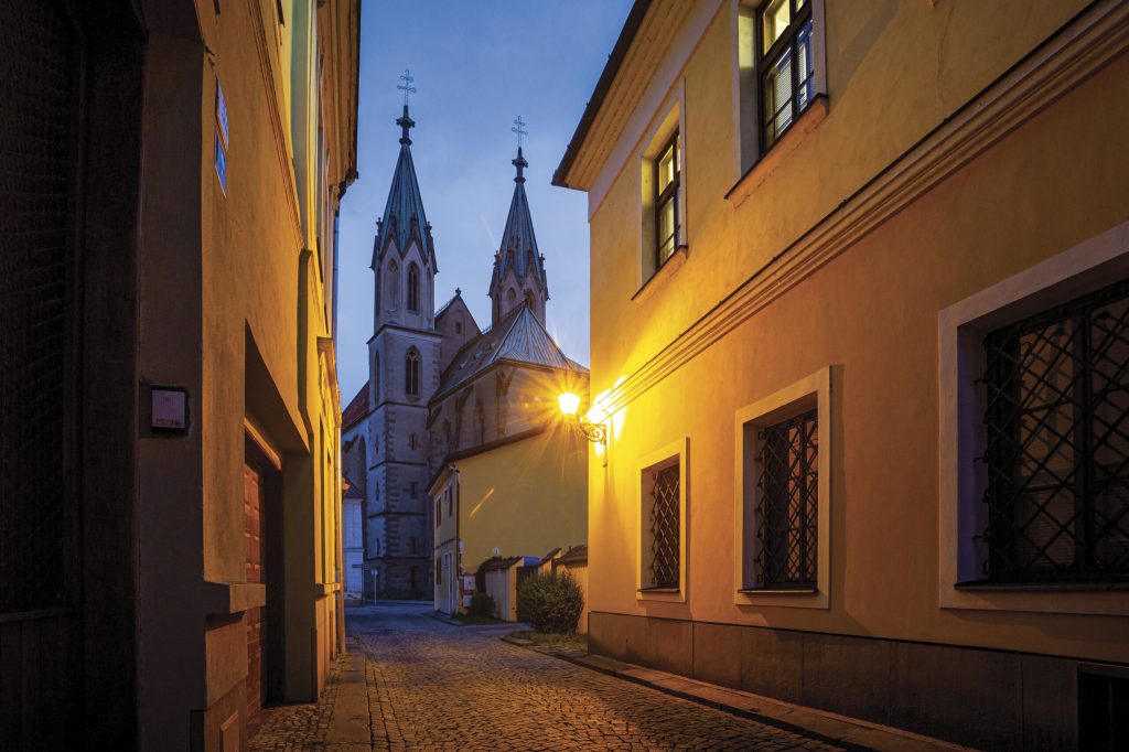 Osvětlená večerní ulice s pohledem na kostel svatého Mořice